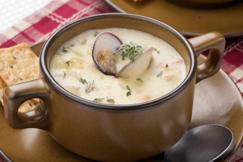 Bowls of hot delicious clam chowder garnished with fresh thyme, and multy grain crackers