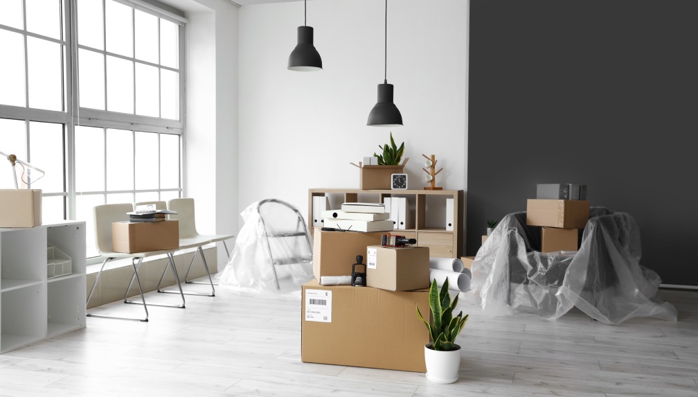 Cardboard boxes with belongings in interior of office on moving day