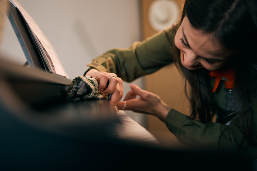 woman checking and cleaning piano.